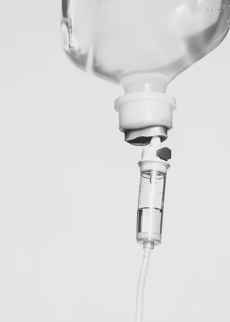 Infusionsflasche mit Tropfkammer und Schlauch vor hellem Hintergrund, Detox-Infusion